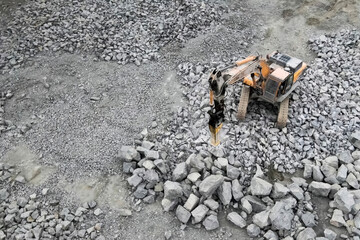 Hydraulic hammer on excavator chassis, works in the quarry crush