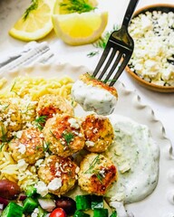 Forkful of delicious Greek Chicken Meatballs with Tzatziki Sauce and Orzo