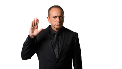 Serious man in black suit raises hand in gesture against dark background