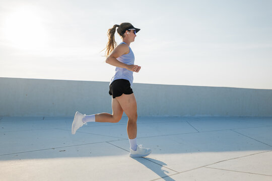 An enthusiastic runner relishes the experience of a bright, sunny morning jog atop a rooftop, surrounded by a clear blue sky