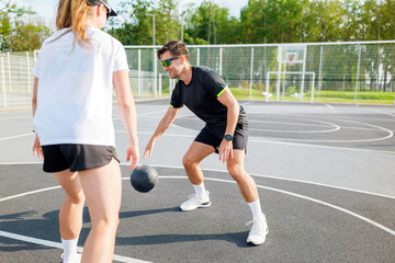 Dribbling and practicing basketball skills between two friends on an outdoor court during a sunny day