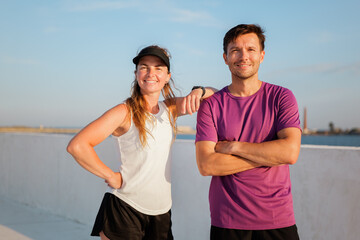 Motivated fitness enthusiasts posing confidently against a vibrant sky, capturing the spirit of an...
