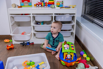 A baby sits on the floor, happily playing with toys