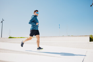 Energetic runner enjoying a sunny jog along a modern outdoor pathway in an urban park setting