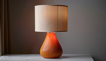 a modern table lamp with an orange ceramic base and a textured beige lampshade