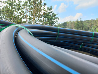 Black HDPE pipes with blue stripe for water supply outdoors