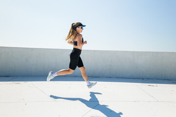 Runner enjoys a sunny day while sprinting on a rooftop track with determination and focus in each...