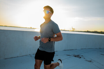 Runner embracing the glow of sunset during evening jog along the waterfront pathway near the city...