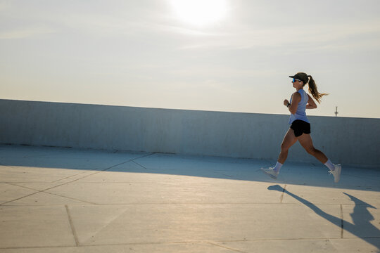 Running in the warm sunlight, a determined individual embraces fitness on an urban rooftop