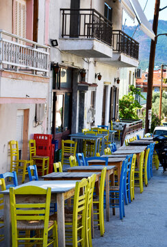 Blue and yellow tables and chairs on a street tavern in Limenaria, Greece stock photo images. Picturesque restaurant in Limenaria resort photo images. Greek street tavern photo