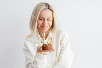 Portrait of happy middle aged woman holding birthday cake with lit candles