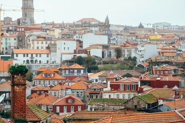 Dense cityscape displays vibrant terracotta rooftops in Porto, Portugal. A church spire and a...