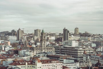 A wide vista of Porto unfolds under a gray sky. Clerigos Church rises majestically amidst a sprawl...