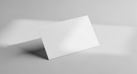 A blank white horizontal card stands upright on a light grey surface, featuring soft shadows and ample copy space for design mockups.