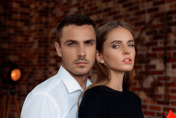 Confident Couple in Formal Attire Against Brick Wall