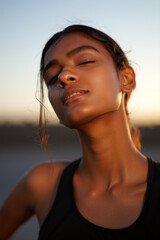 A young woman basks in the warm glow of the sunset, showcasing her confidence and natural beauty while wearing athletic attire. Generative AI.