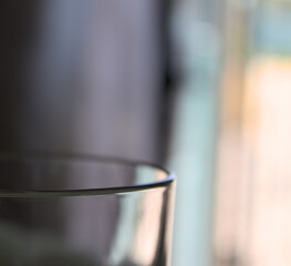 Glass cup on table in front of open window