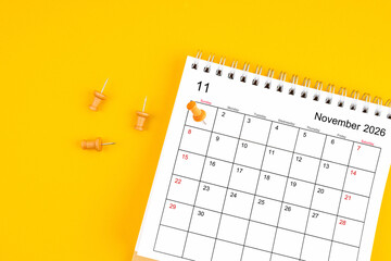 November 2026 Monthly desk calendar for 2026 year with wooden pin on yellow background.