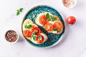 Fresh homemade caprese sandwich with avocado paste, mozzarella cheese, cherry tomatoes, fresh aromatic basil leaves and spicy hot oil top view. Healthy homemade food concept.