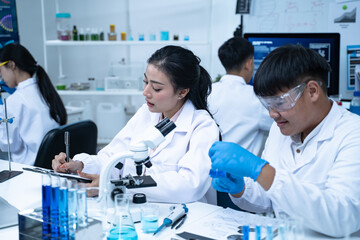 In the laboratory, a group of professional researchers gather around a chemical tube, checking samples for medical analysis and conducting chemistry experiments to ensure accurate results.
