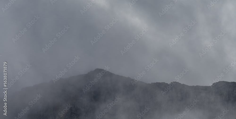 Wall mural panorama looking through mist and fog at a distant mountain range creating a mysterious spooky looki