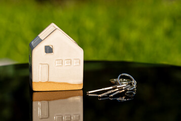 Real estate concept with ceramic house model and keys symbolizing home ownership, property...