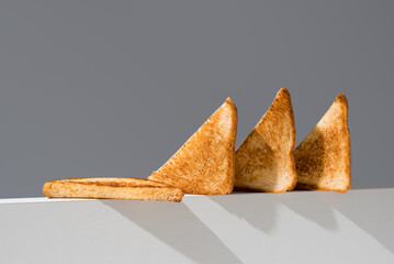 Triángulos de pan tostado dorados para sándwiches en un soporte blanco sobre fondo gris