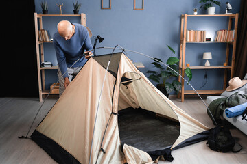 elderly man setting up camping tent at home