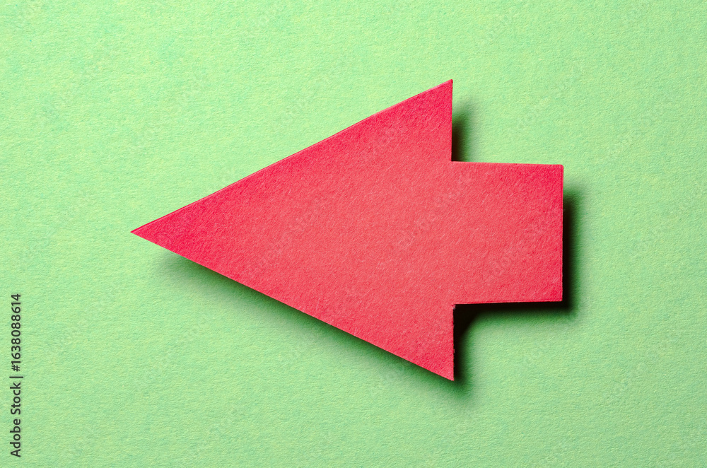 Poster red cut out blank paper cardboard arrow direction sign with copy space for text on green background,
