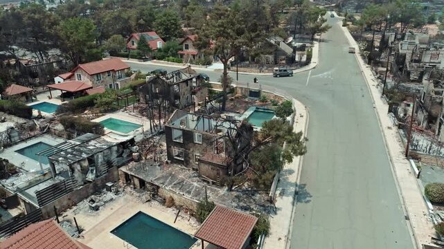 Aerial view of the city area after a forest fire. Ecological disaster, burnt houses and trees, empty streets.