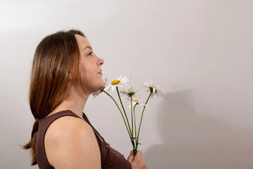 A woman stands with her profile visible, holding a bouquet of daisies. She exudes a sense of calm...