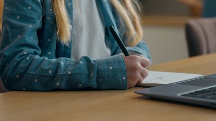 Close up unrecognizable Caucasian girl schoolgirl child kid daughter preparing school homework study writing notes learn at home kitchen e-learning with online teacher using laptop watching course