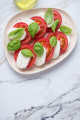 Italian classic caprese salad on a white granite background, vertical shot, copy space, flat lay