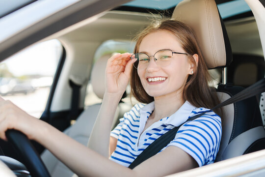 Young woman adjusting glasses while driving car