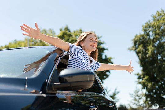 Fototapeta Happy tourist girl leaning out of car window enjoying road trip
