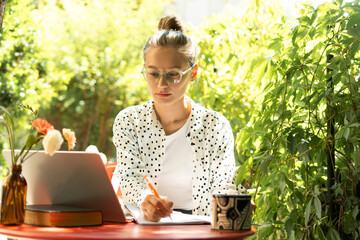 Focused freelancer working remotely in lush green garden