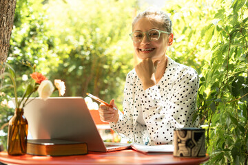 Freelancer working remotely from garden cafe enjoying nature