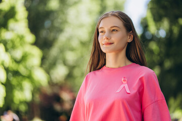 Young woman wearing pink ribbon is supporting breast cancer awareness in park
