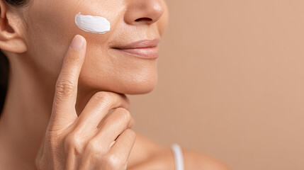 Naklejka premium Woman applying moisturizing cream on face with smooth skin