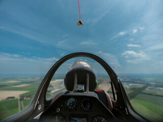View from glider cockpit showing tow rope or drogue parachute above rural countryside during flight