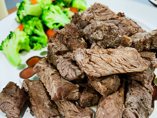 Grilled beef steak served with steamed carrots and broccoli on a plate.