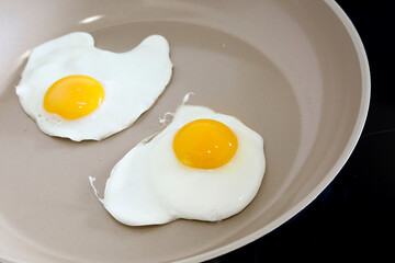 Fresh eggs being fried on ceramic pan