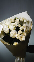 Beautiful white roses in a flower shop. Florist assembles a bouquet to order