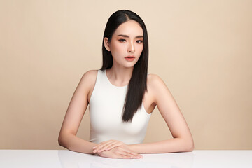 A beautiful young Asian woman with clean, fresh skin against a beige background. Skincare, facial...