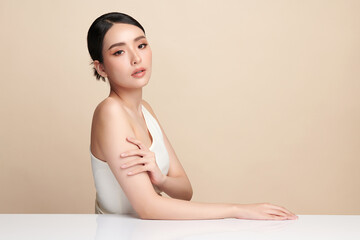 A beautiful young Asian woman with clean, fresh skin against a beige background. Skincare, facial...