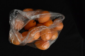 Close up apricots in plastic bag, black background, separated, negative space, copy space,