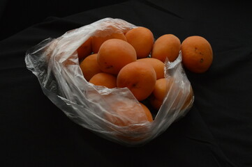 Close up apricots in plastic bag, black background, separated, negative space, copy space,