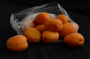 Close up apricots in plastic bag, black background, separated, negative space, copy space,