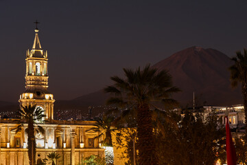 The sun sets over the Plaza de Armas in Arequipa, casting golden light on the majestic Basilica...