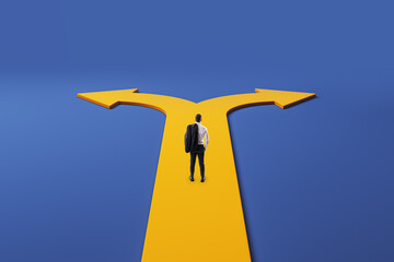 Businessman standing at forked yellow path, choosing between two directions against a blue...
